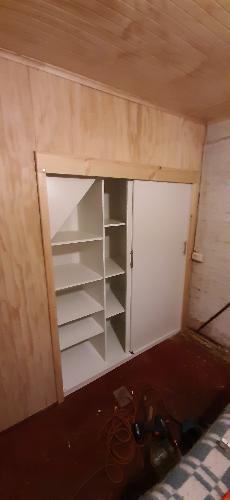 Closet con Puertas correderas bajo escalera en Tableros Melamina Blanca. Adems cubriendo la Pared con Tableros ranurados. 